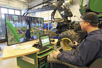 Lauri Kuivila harjoittelee Koulutuskeskus Valossa metsäkonesimulaattorilla puiden kaatamista ja pinoamista oikeaan paikkaan.