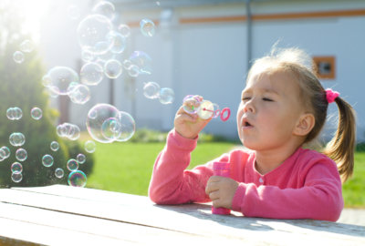 Little girl is blowing soap bubbles